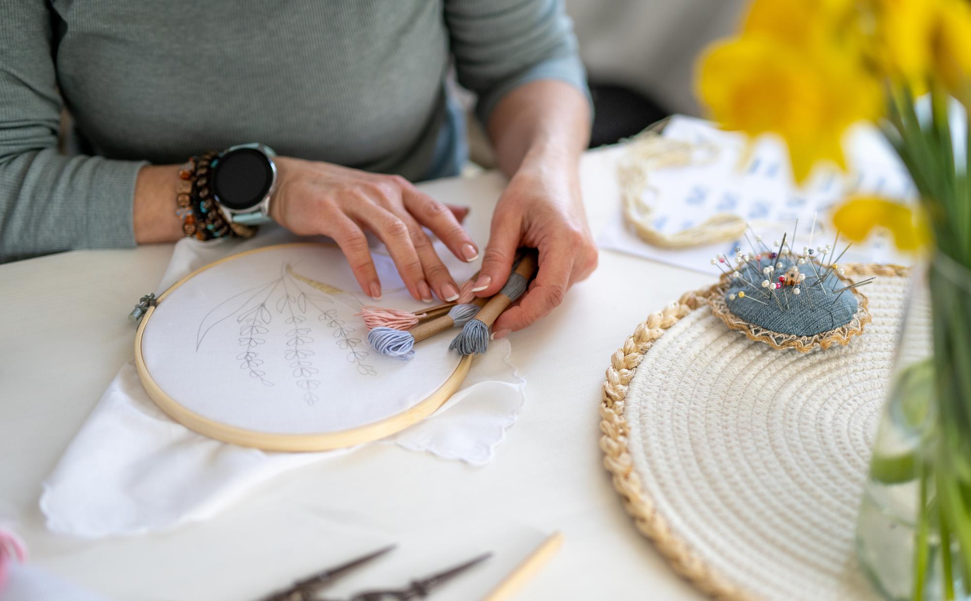 Workshop hands embroidering a floral pattern